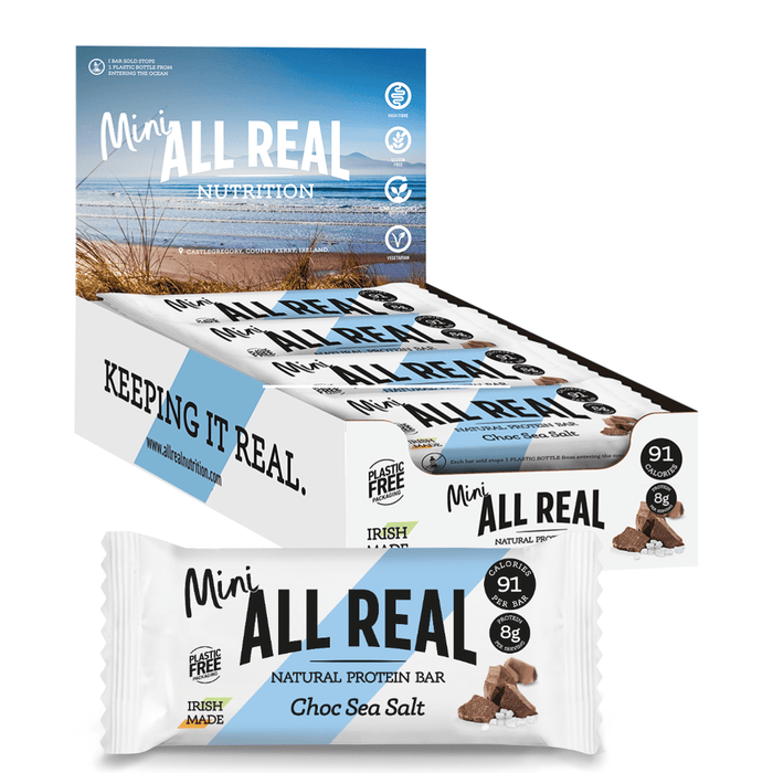 Packaging of All Real Mini Protein Bars showing the product name and 'Choc Sea Salt' flavor, with an image of a beach and waves in the background.