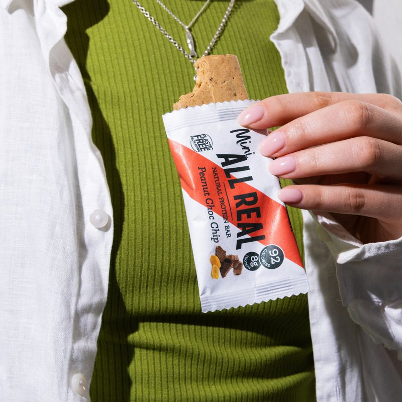Person holding All Real mini peanut chocolate chip protein bar