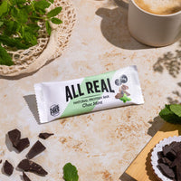 All Real chocolate mint protein bar with fresh mint leaves and chocolate pieces