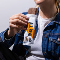 Person holding All Real chocolate orange protein bar with bite