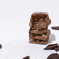 All Real chocolate sea salt protein bar stack with chocolate pieces