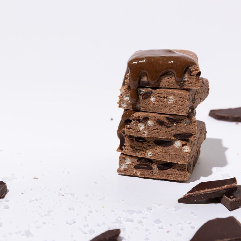 All Real chocolate sea salt protein bar stack with chocolate pieces