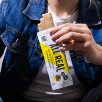 Person eating All Real lemon coconut protein bar