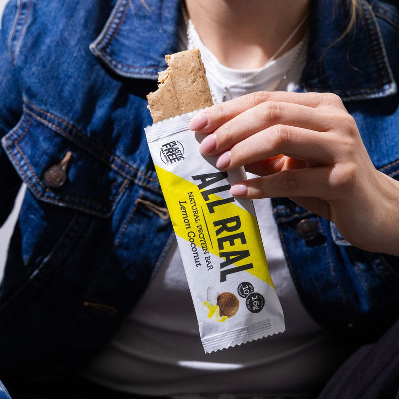 Person eating All Real lemon coconut protein bar