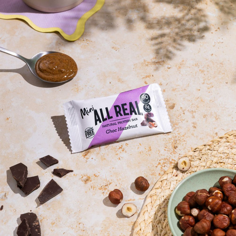 Mini All Real chocolate hazelnut protein bar with hazelnuts and chocolate pieces in lifestyle scene