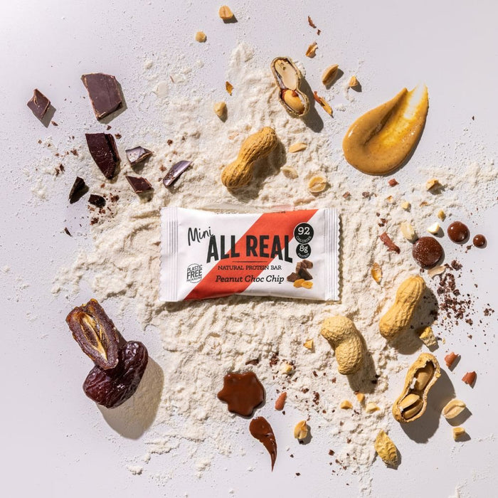 Mini All Real peanut chocolate chip protein bar with peanuts and chocolate chips on ingredient scatter