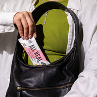 Hand placing All Real peanut butter protein bar into bag