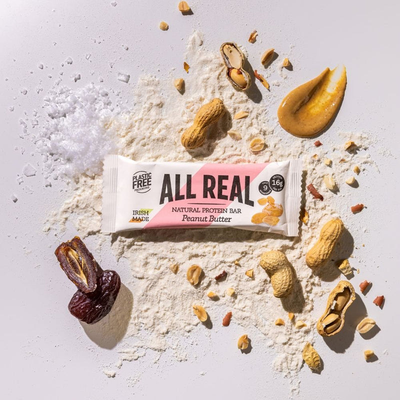 All Real peanut butter protein bar with peanuts and peanut butter on ingredient background