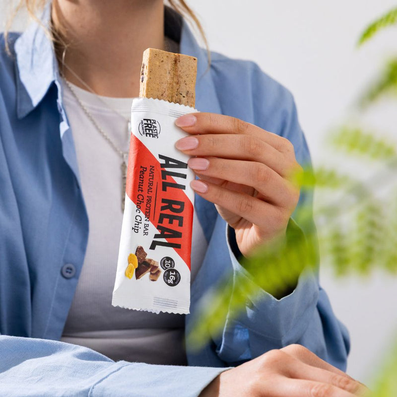 Person enjoying All Real peanut chocolate chip protein bar
