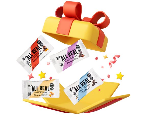 Four All Real protein bars spilling out of a colorful gift box on a white background
