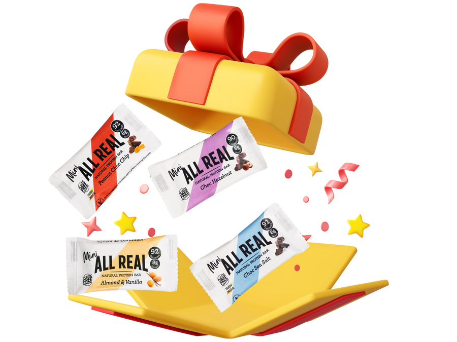 Four All Real protein bars spilling out of a colorful gift box on a white background